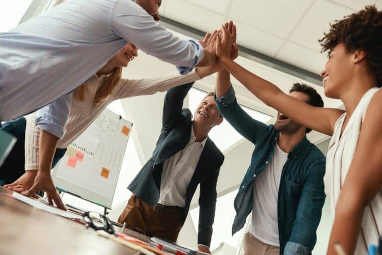We did it Business people giving each other high-five and smiling while working together in the